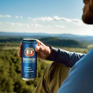 man drinking na beer on hilltop